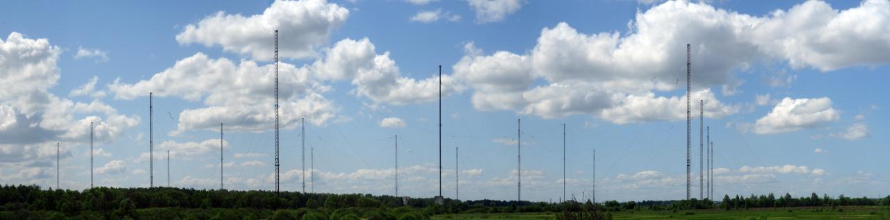 Panorama of a long row of tall masts under clouds