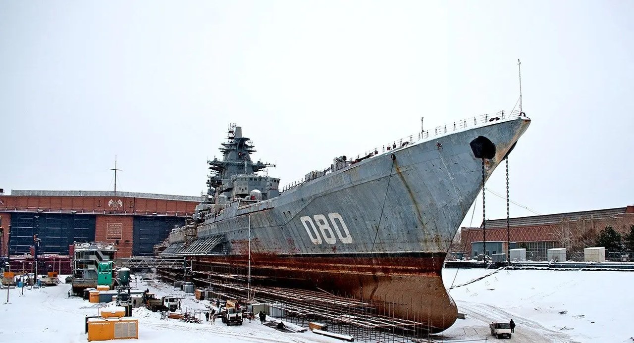 Kirov-class cruiser with hull number 080 in dry dock in snow, rusted lower hull and scaffolding