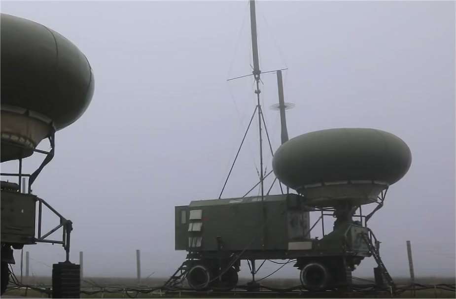 Two radome trailers in fog beside a guyed mast