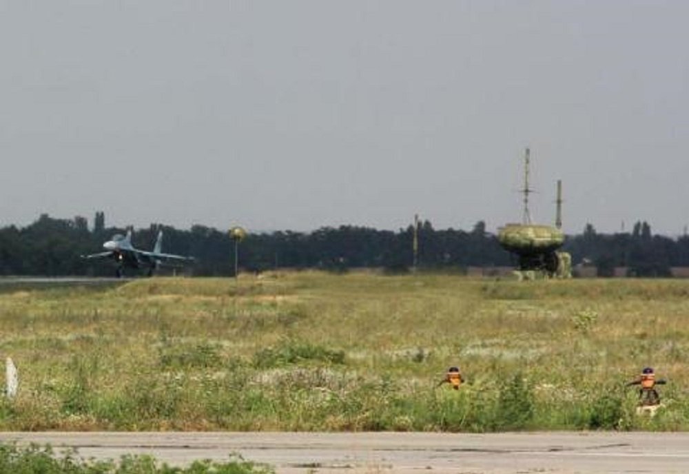 Su-27 landing at an airfield with a radome beacon trailer at right