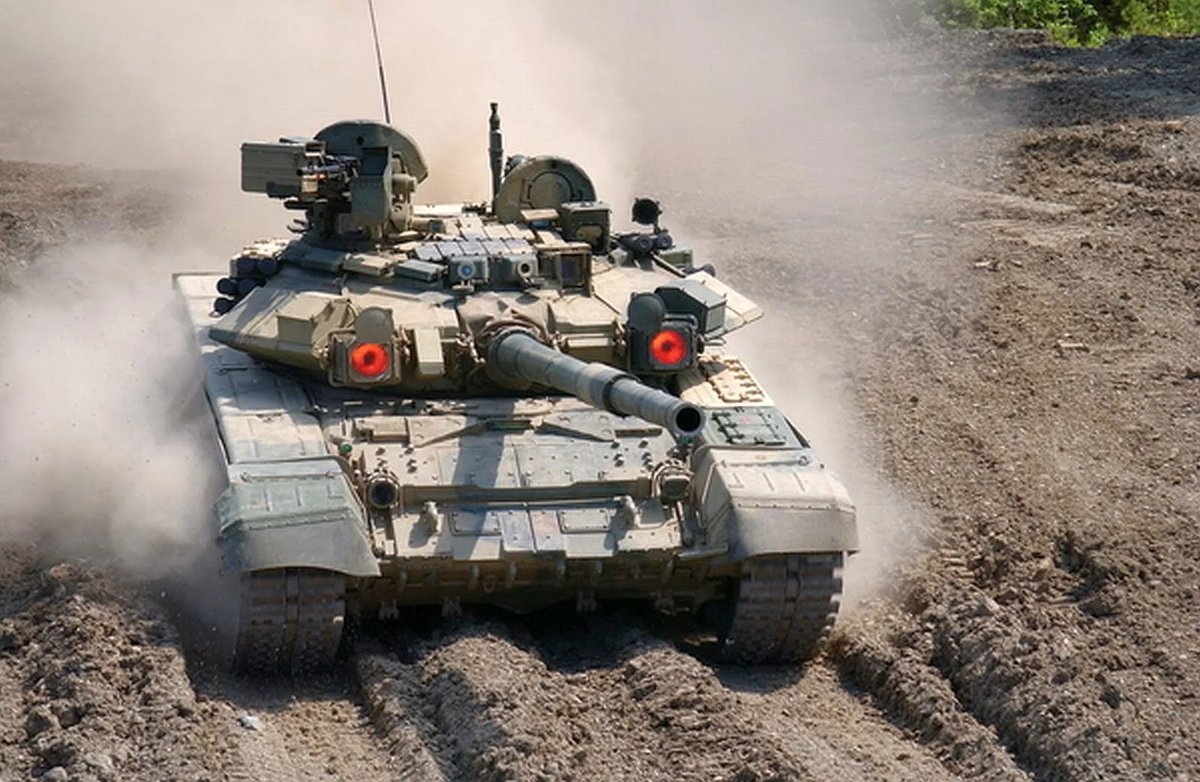 T-90 driving through dust with dazzlers lit