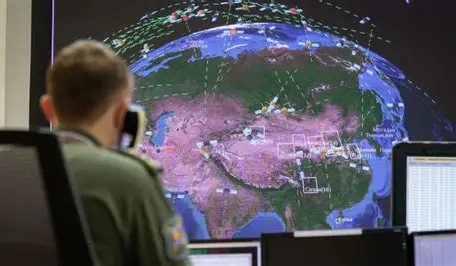 Officer at SPRN-style command console facing a large map display